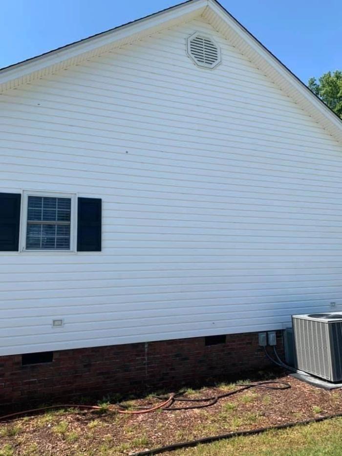 White vinyl siding and brick foundation after a soft wash by Clayton Pressure Washing