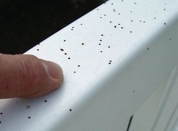Close view of shingle grit and debris left on a white gutter face before cleaning
