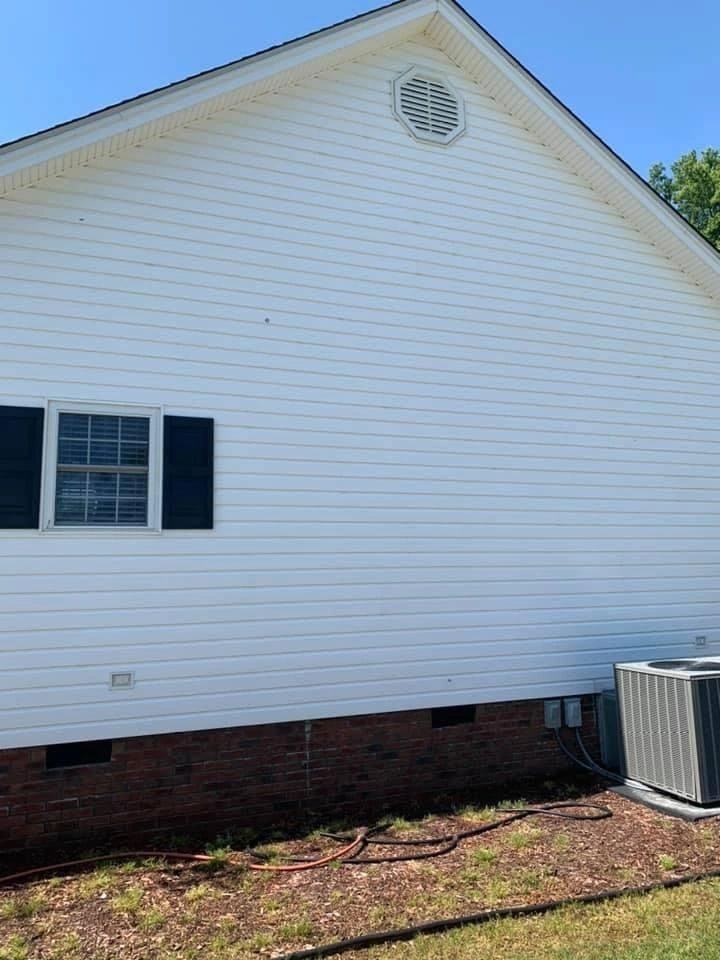 White vinyl siding and brick foundation after a soft wash by Clayton Pressure Washing