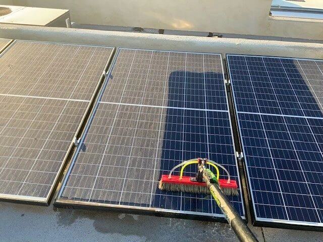 Rooftop solar panels being cleaned with a soft brush and pure water