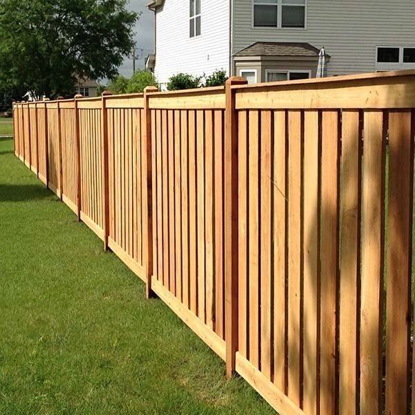 Wood privacy fence running along a lawn after cleaning