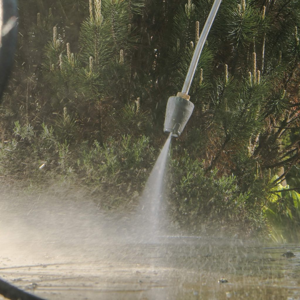 Pressure washing technician cleaning exterior surface in Apex, NC