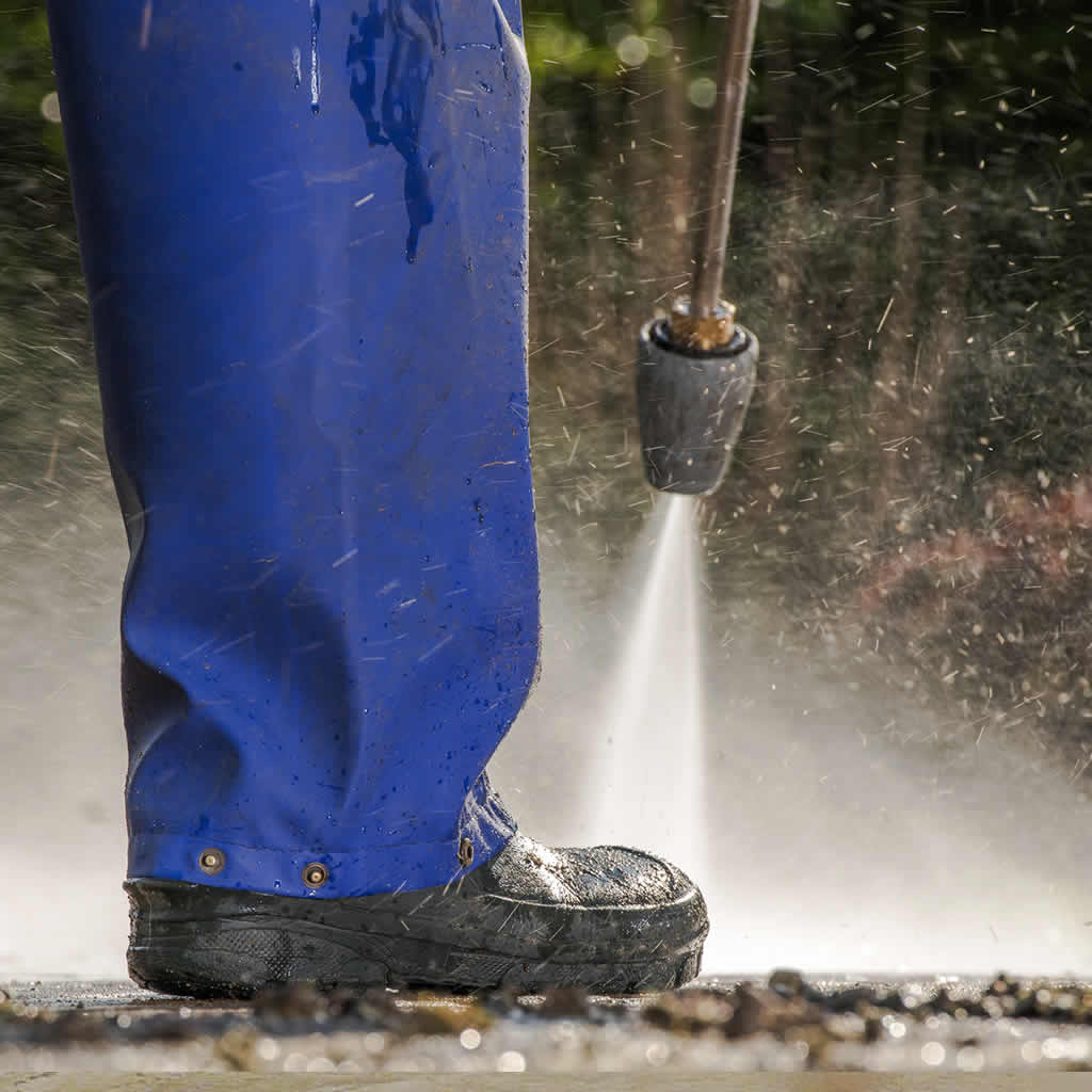 Power washing technician cleaning an exterior hard surface in Apex NC